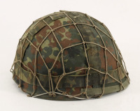 Lote 194 - CAPACETE MILITAR - Em ferro com cobertura de tecido camuflado e rede. Interior em couro com correias em tecido. Tamanho 55-57