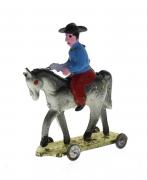 Lote 1265 - Cowboy a cavalo em chapa esmaltada sobre base com rodas, provavelmente de fabrico português, sinais de uso e ferrugem na base ( 11 x 13 cm )