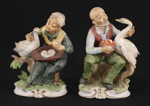 Lote 31 - ESCULTURAS EM BISCUIT - Par de figuras de anciãos sentados com gansos e cestos. Decorações policromadas. Dim: 17 cm