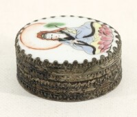 Lote 73 - CAIXA ORIENTAL - Made in Beijing, China. Formato oval em metal prateado com relevos, tampa em porcelana policromada com figura feminina. Dim: 2x4x5,5 cm