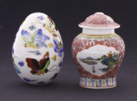 Lote 94 - OVO DECORATIVO E POTE EM PORCELANA - Conjunto de 2 peças em porcelana com decoração policromada com borboletas e paisagem oriental com flores. Dim: 8 cm. Nota: pote com pequena falha