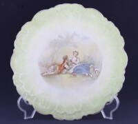 Lote 198 - PRATO DECORATIVO, FAIANÇA - Prato decorativo em faiança, decoração em tons de verde e com cena galante, com marca na base Lopes & Ca, Alcantara, Portugal.. Dim.: 23 cm Nota: com sinais de armazenamento