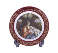 Lote 209 - GLORIA/BAVARIA, PRATO EM PORCELANA - Decoração policromada com "Cena Maternal", aba com motivos vegetalista a dourado em fundo bordeaux, marcado na base. Dim: 19 cm