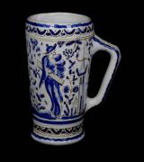 Lote 20 - Caneca em cerâmica, marcada na base, numerada (166-4-N49), pintada à mão em tons de azul com figuras, com 19 cm de altura. Nota: apresenta sinais de uso
