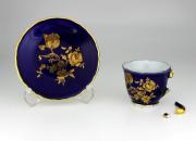 Lote 21 - Chávena miniatura com pires em porcelana Porart, decoração floral com dourados sobre azul, marcas na base, para coleccionadores. Nota: Defeito, asa partida