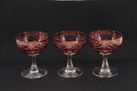 Lote 164 - TAÇAS DE CHAMPAGNE EM VIDRO - 3 taças em vidro bordeaux com decoração lapidada. Fuste e base em vidro translucido. Dim: 12 cm