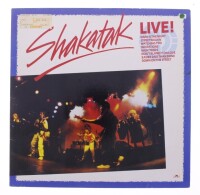 Lote 75 - SHAKATAK - "LIVE" - Disco de vinil, LP de 33 rpm, de 1985, editora POLYDOR. Capa em bom estado (com etiquetade preço) e disco sem sinais de uso. Inclui encarte original. Fabricado e editado na Alemanha