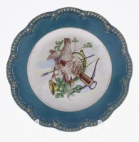 Lote 343 - FÁBRICA DE SACAVÉM, PRATO EM FAIANÇA - Decoração policromada com cena de caça, aba recortada em tom verde com ornamentos dourados, marcado na base. Dim: 33 cm. Nota: sinais de uso