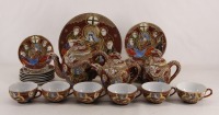 Lote 377 - SERVIÇO DE CHÁ EM PORCELANA ORIENTAL - Decoração policromada e dourada estilo Satsuma com figuras composto de bule, açucareiro, leiteira, 6 chávenas de chá com 7 pires, 7 pratos de doce e 1 prato para bolos. Dim: 18 cm (bule)