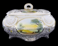 Lote 378 - RB ALCOBAÇA, CAIXA EM FAIANÇA - Caixa oval com tampa, decoração policromda com paisagens em reservas e ornamentos dourados, marcada na base. Dim: 15x23x17 cm. Nota: sinais de uso