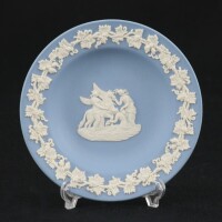 Lote 213 - WEDGWOOD, COVILHETE EM PORCELANA - Decoração relevada a branco com figuração clássica e elementos vegetalistas em fundo azul claro, marcado na base, Made in England. Dim: 11 cm