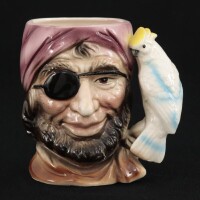 Lote 150 - TOBY MUG - Caneca em forma de pirata, faiança com decoração policromada e pega em forma de arara, marcada na base. Dim: 13 cm