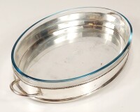 Lote 85 - TRAVESSA EM CASQUINHA CONTENDO TRAVESSA EM PYREX - travessa oval em casquinha de prata com quatro pés, friso decorativo junto ao rebordo e pegas laterais, contendo travessa Pyrex modelo 347 1L. Pequenos sinais de uso. Dimensões (da travessa em c