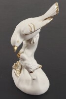 Lote 54 - ESCULTURA EM PORCELANA BISCUIT - representando pássaro alimentando cria em cima de um ramo, em porcelana biscuit, com apontamentos de vidrado e dourado. Mínimos sinais de uso. Altura: 14,8 cm