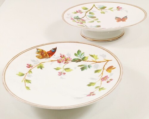 Lote 58 - PAR DE PRATOS DE BOLO EM PORCELANA MINTON SÉCULO XIX - conjunto de dois pratos de bolo, com pedestal, pintados à mão em policromia com ramo florido e borboleta e rebordo com dois filetes a ouro, dos quais o interno polilobado, produção típica do