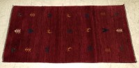 Lote 87 - TAPETE PERSA GABBEH (1.44M2) - Lã alta e natural feito à mão. Decoração simples em fundo vermelho com figuras, animais e simbologia nómada. 166x87cm. Como Novo. Muito confortável. Tapete idêntico com PVP de 1.077,18 €. Tapetes Gabbeh são tapetes