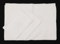 Lote 70 - LENÇOL E ALMOFADAS DE LINHO COM BORDADOS - Conjunto de lençol e par de almofadas em tecido de linho branco com flores bordadas à mão. Dim: 230x166 cm e 40x55 cm (almofadas). Nota: sem uso