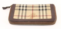 Lote 106 - BURBERRY, CARTEIRA DE SENHORA - Em tela com padrão de tartan e pele castanha. Fecho de correr. Interior compartimentado. Dim: 12x20 cm. Nota: sinais de uso