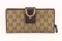 Lote 136 - GUCCI, CARTEIRA DE SENHORA - Em tecido castanho com padrão de logotipos e pele castanha. Fecho de mola. Interior com compartimentos e bolsa com fecho de correr. Dim: 10x19 cm. Nota: sinais de uso