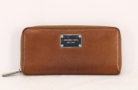 Lote 42 - MICHAEL KORS, CARTEIRA DE SENHORA - Em pele castanha com fecho de correr. Interior com bolsa de fecho de correr e diversos compartimentos. Dim: 10x21 cm